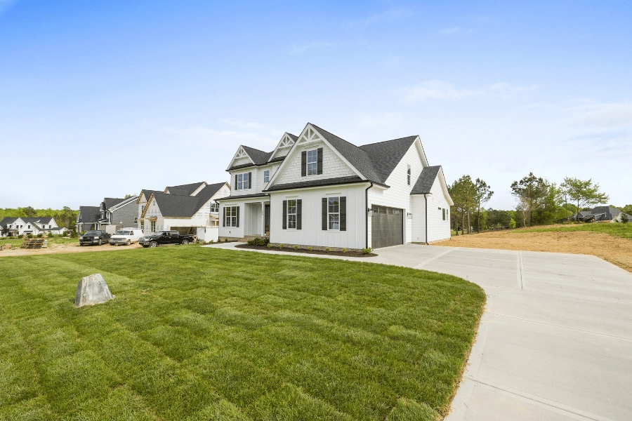Beautiful white home with black shutters and long driveway built in new development 
